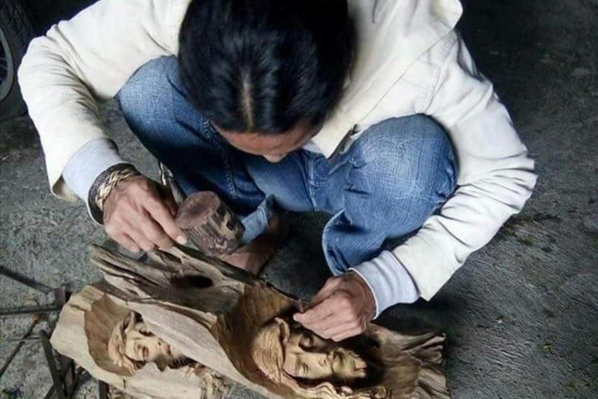 un uomo seduto a terra che guarda un pezzo di legno