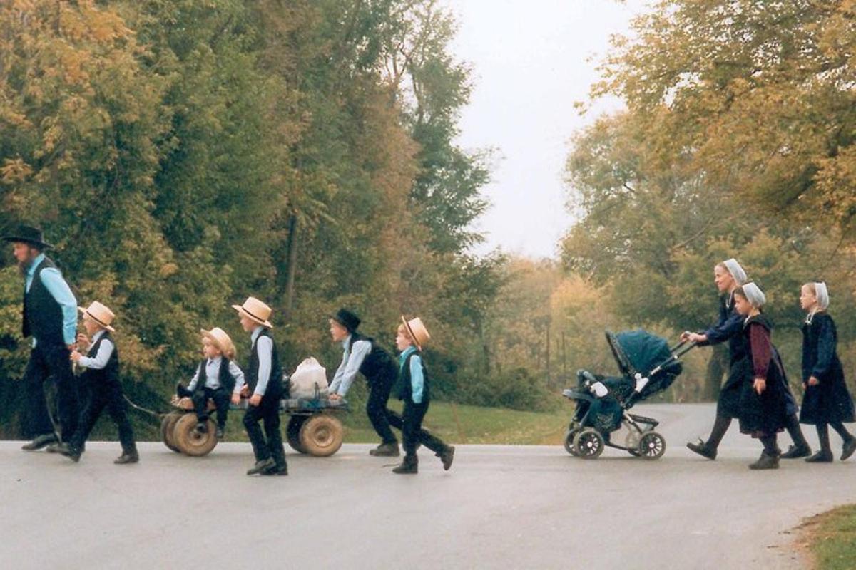 a group of people walking down a street with a baby carriage