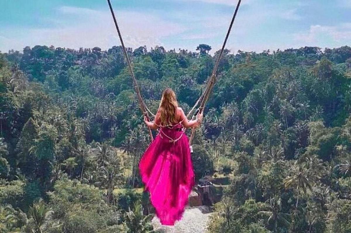 uma mulher de vestido rosa balançando em um balanço