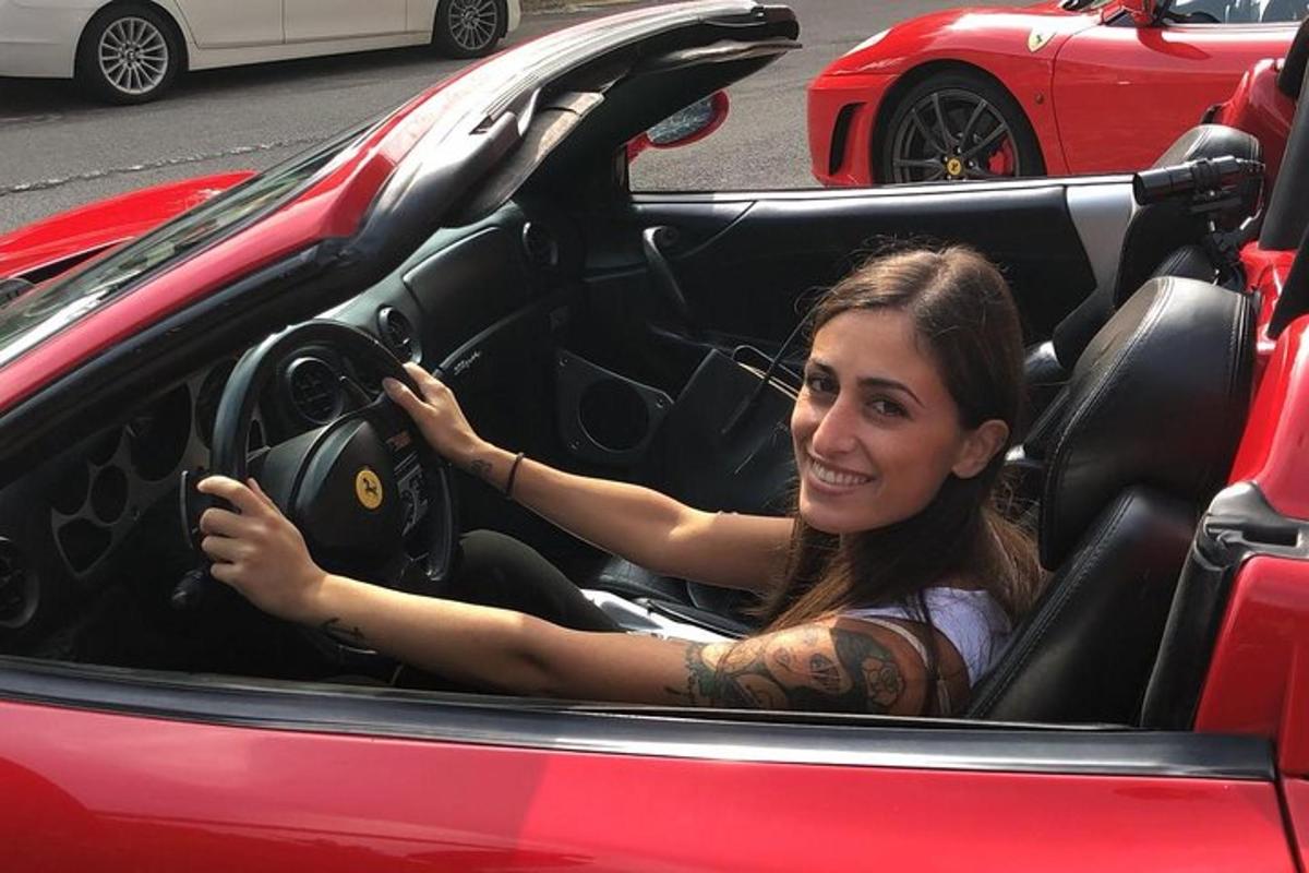 una donna seduta al posto di guida di un'auto rossa
