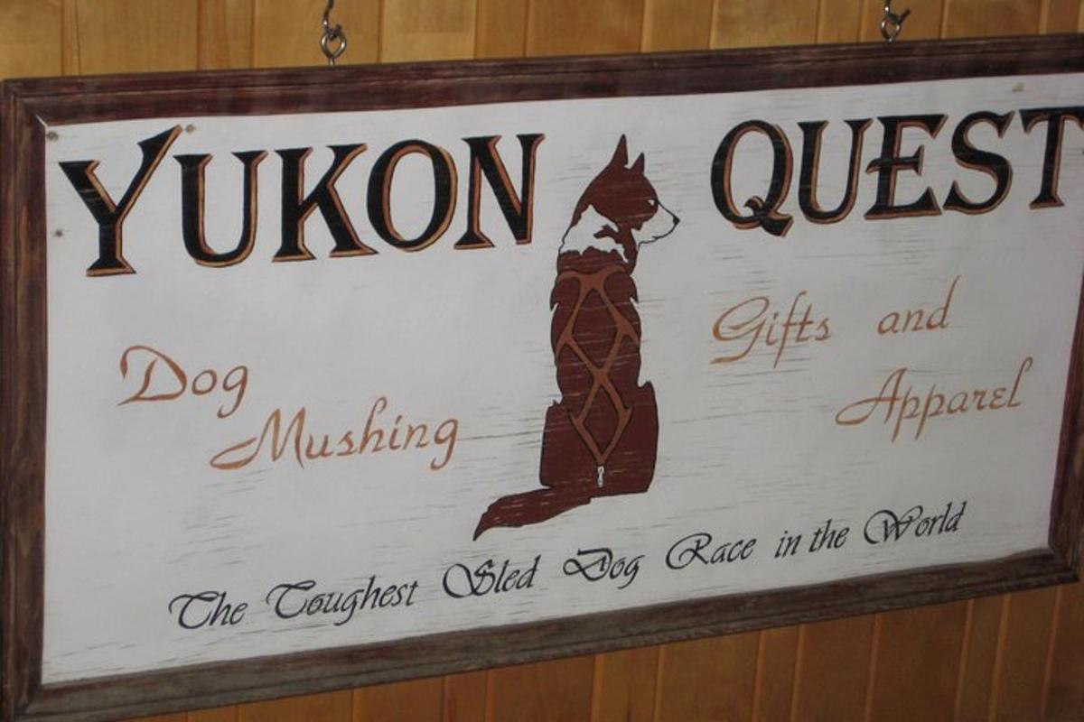 a sign hanging on a wall with a cat on it