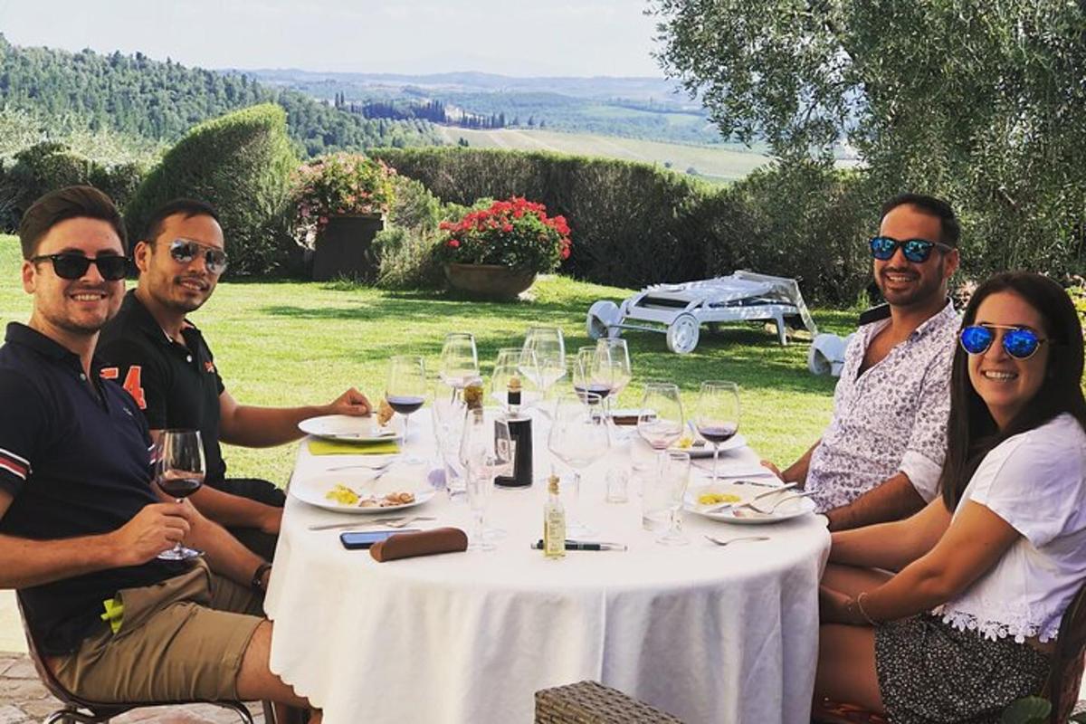un gruppo di persone sedute attorno a un tavolo con bicchieri di vino