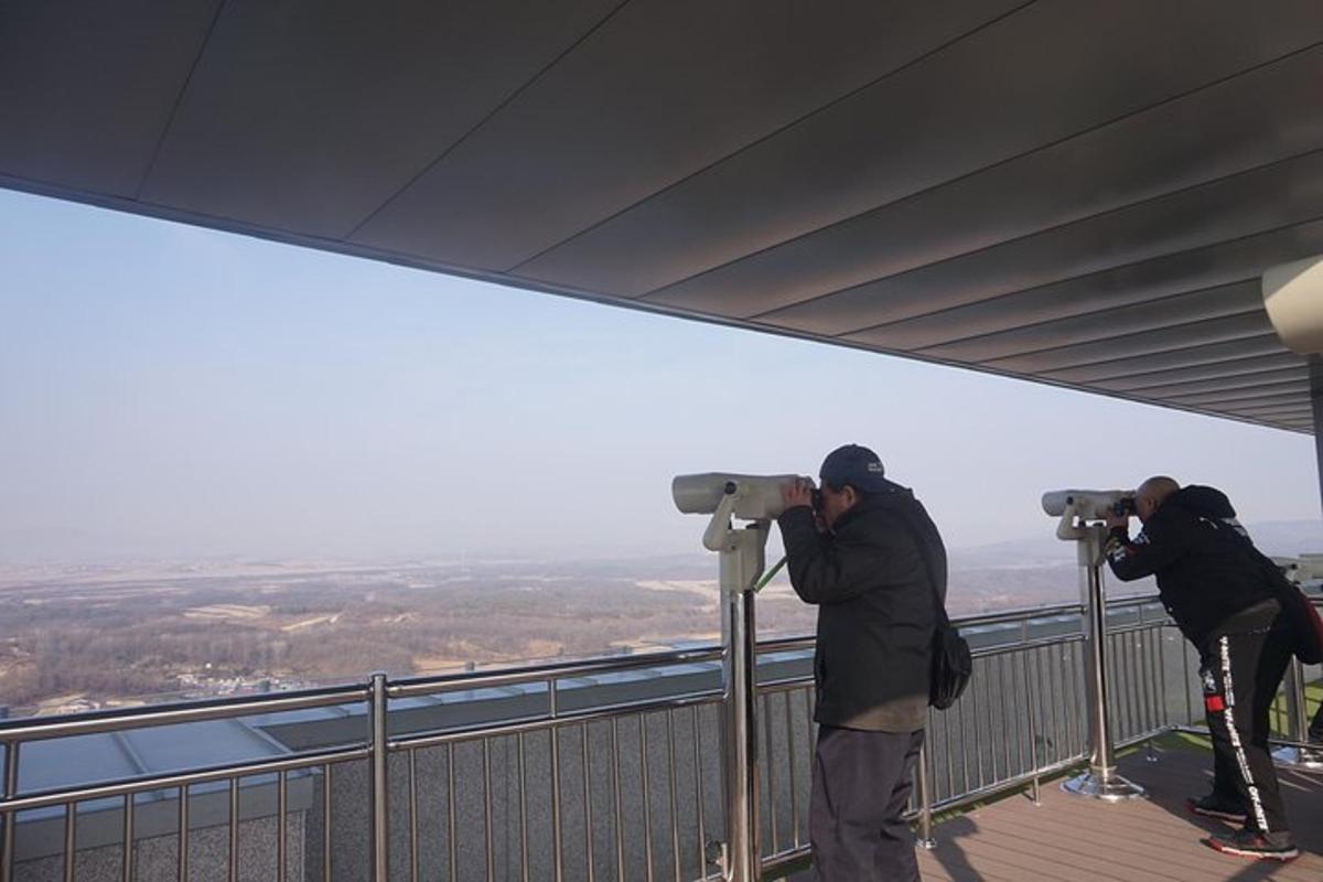 two people taking pictures of the view from the top of a mountain