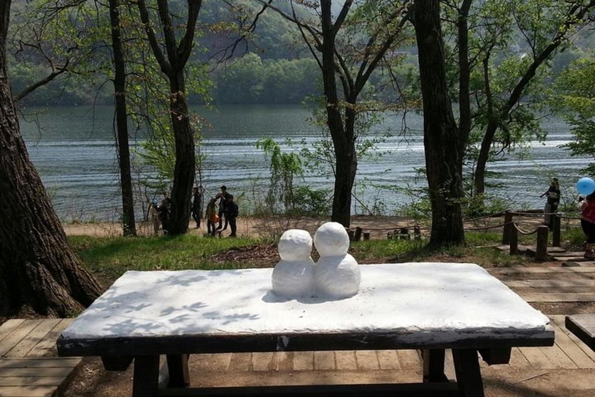 Dos esculturas de hielo sobre una mesa de picnic con vistas a un lago.
