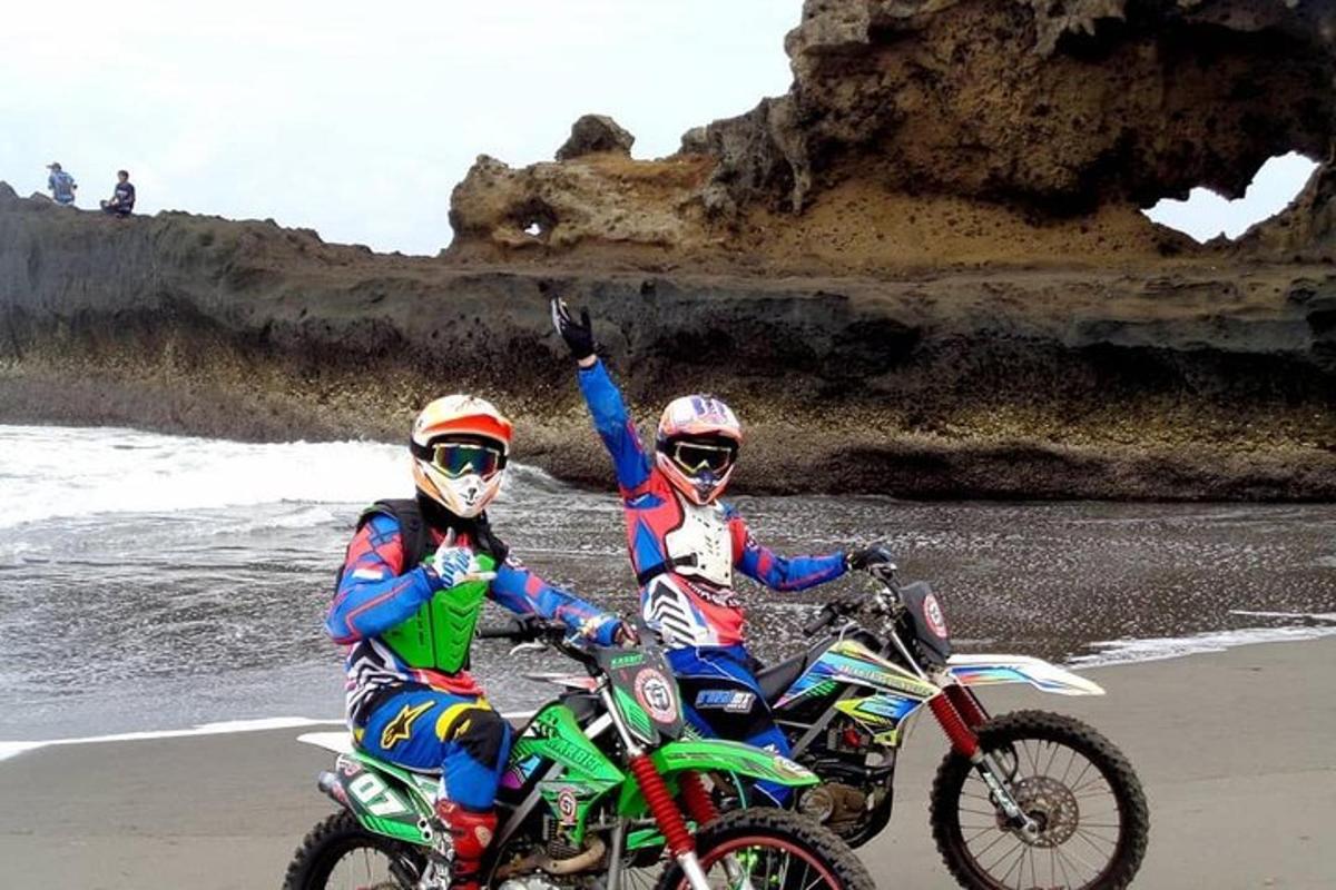 Dos personas montando motos de cross en la playa