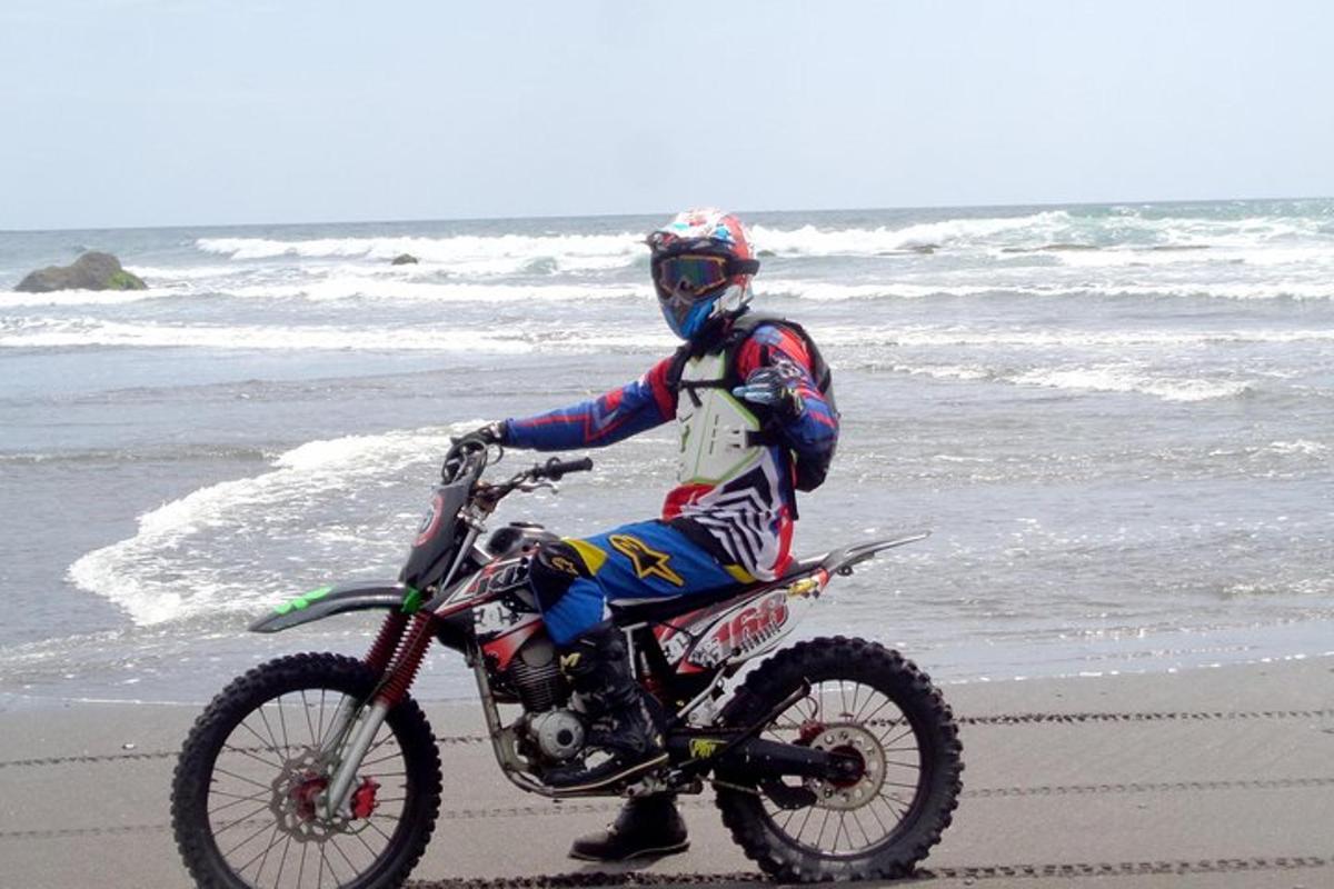 una persona anant amb una moto de cross a la platja