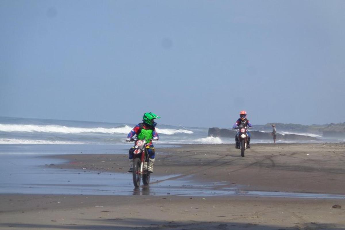 two people riding dirt bikes on the beach