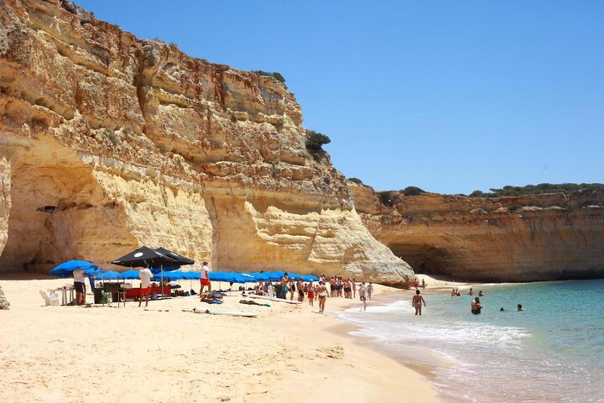 un gruppo di persone su una spiaggia con ombrelloni blu