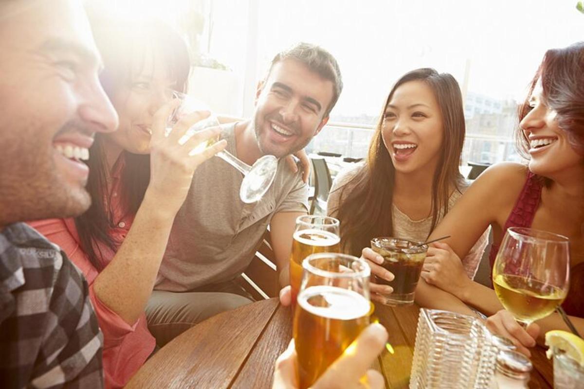 un grup de persones assegudes al voltant d'una taula bevent cervesa