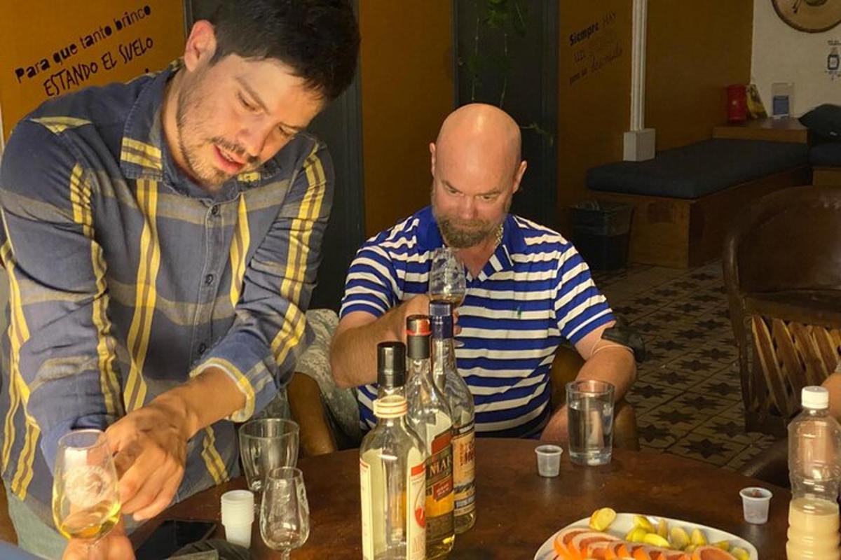 dva muškarca sjede za stolom s bocama vina
