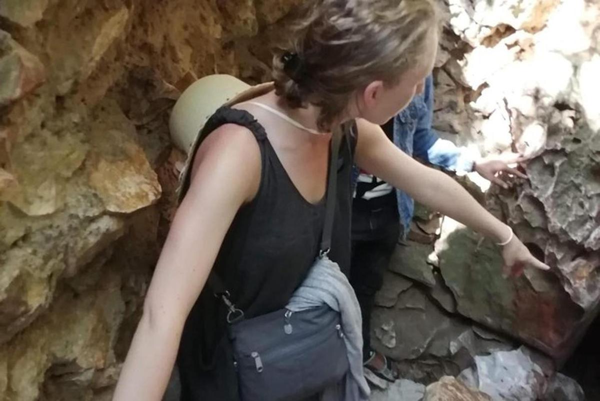 ženska, ki stoji v jami in kaže na skalo