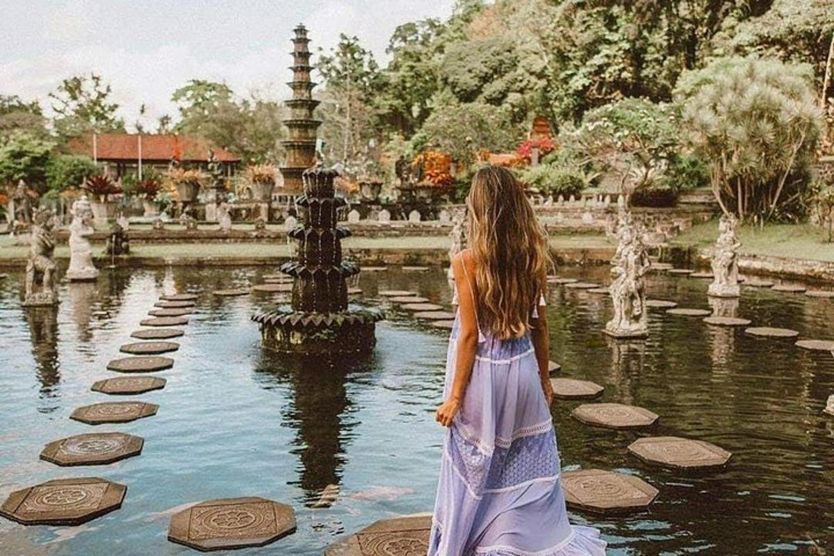μια γυναίκα με φόρεμα που στέκεται μπροστά σε ένα σιντριβάνι