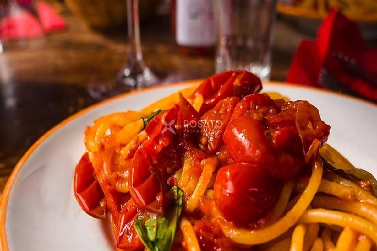 un piatto bianco con pasta, pomodori e salsa