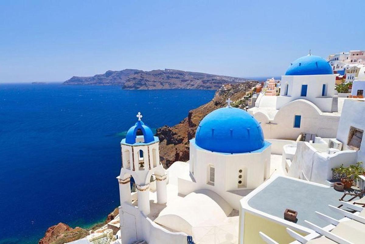 a group of white buildings with blue domes and the ocean