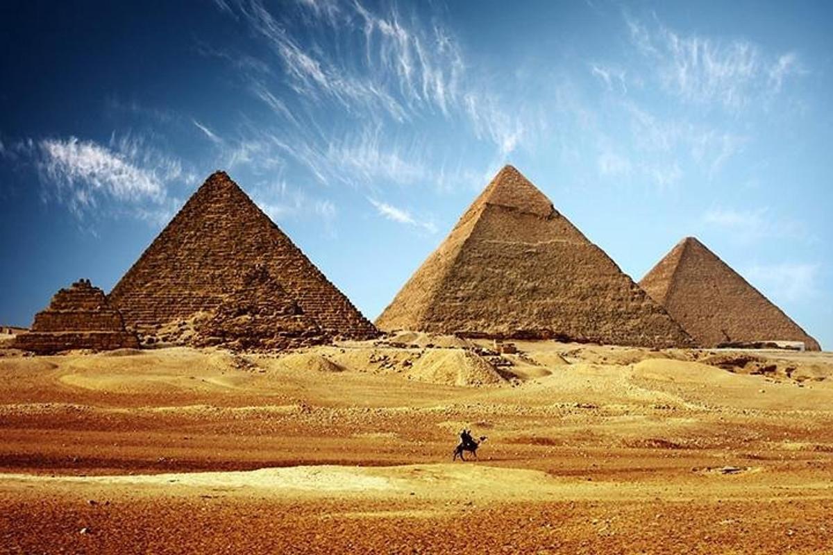 osoba jedoucí na koni před pyramidami