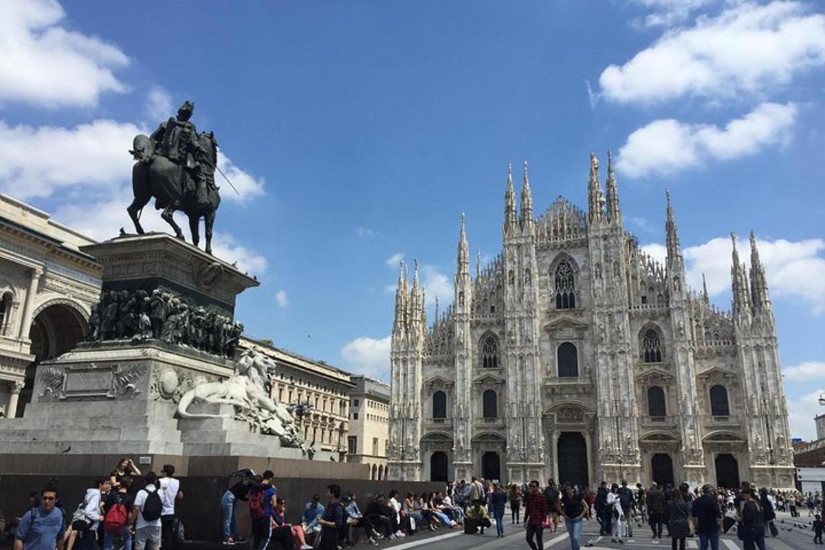 una folla di persone che cammina davanti a un edificio con una statua