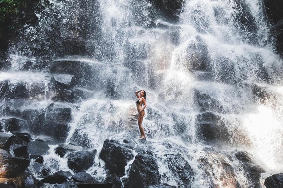a woman standing on a rock in front of a waterfall