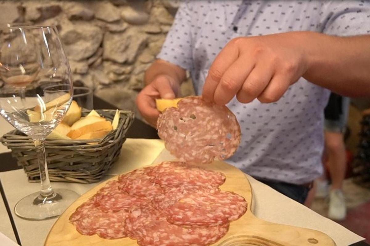 osoba držící kus masa vedle talíře s jídlem