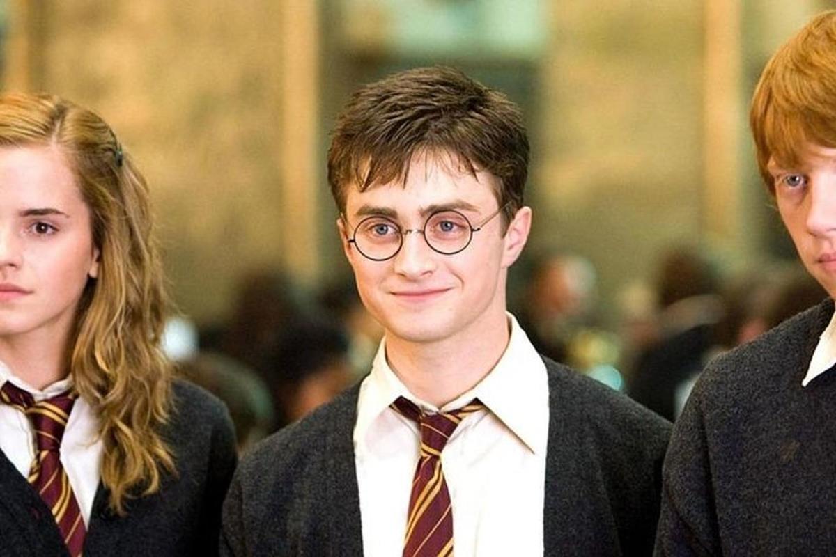 Un joven con gafas de pie entre dos mujeres.