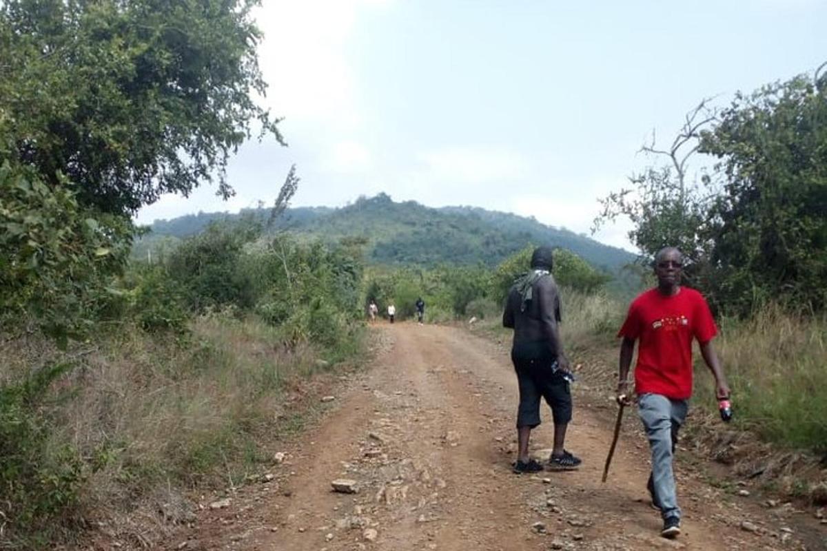 dois homens estão caminhando por uma estrada de terra
