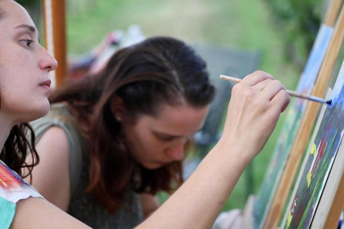 dues noies pinten amb un pinzell sobre un llenç