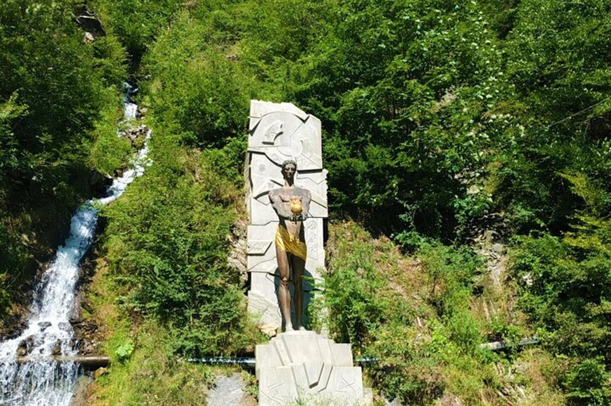 patung di tengah-tengah hutan dengan air terjun