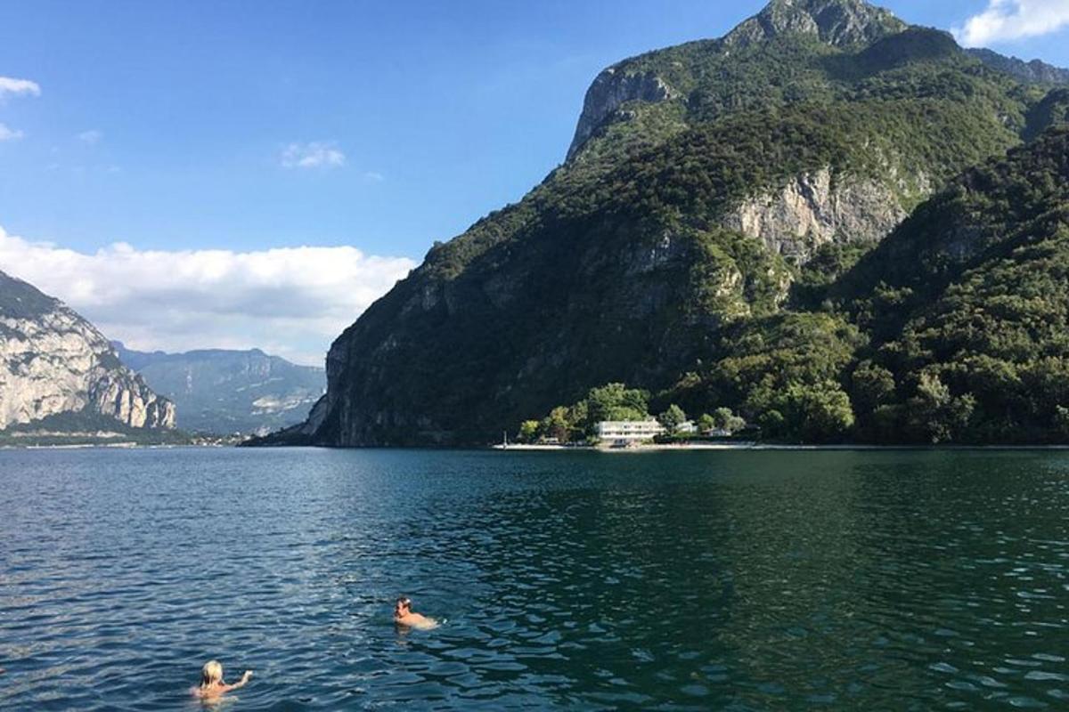 dua orang berenang di tasik di hadapan gunung
