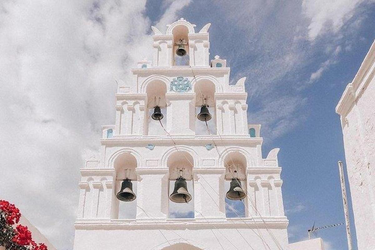 a tall white clock tower with bells on it