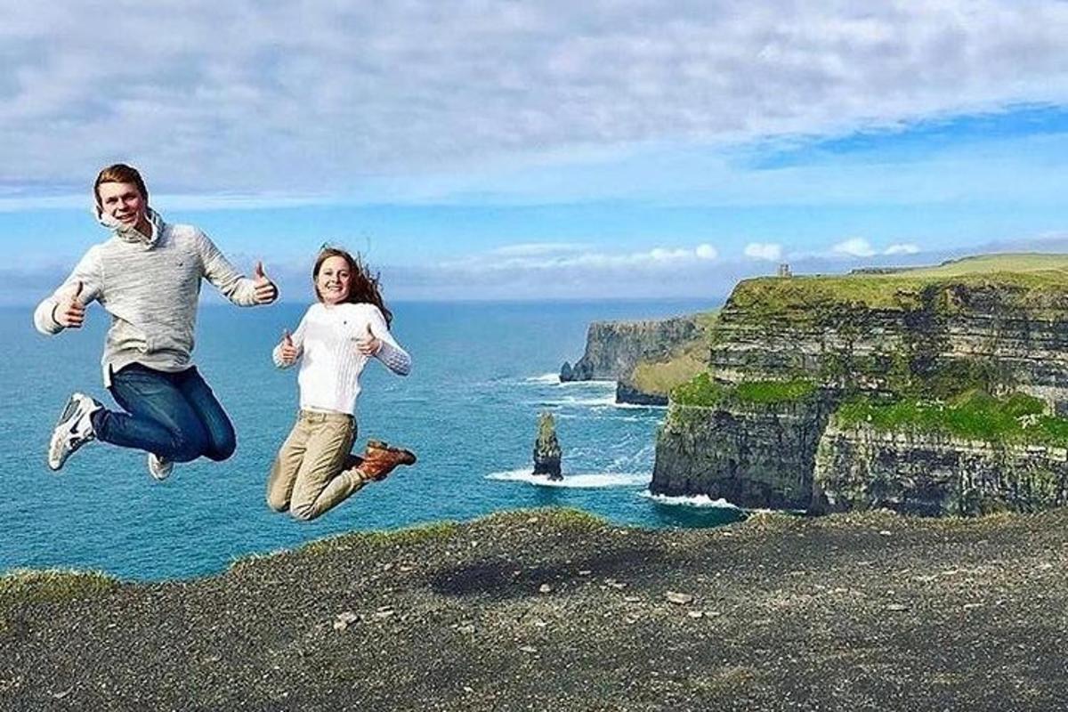 a man and woman jumping in the air near the ocean