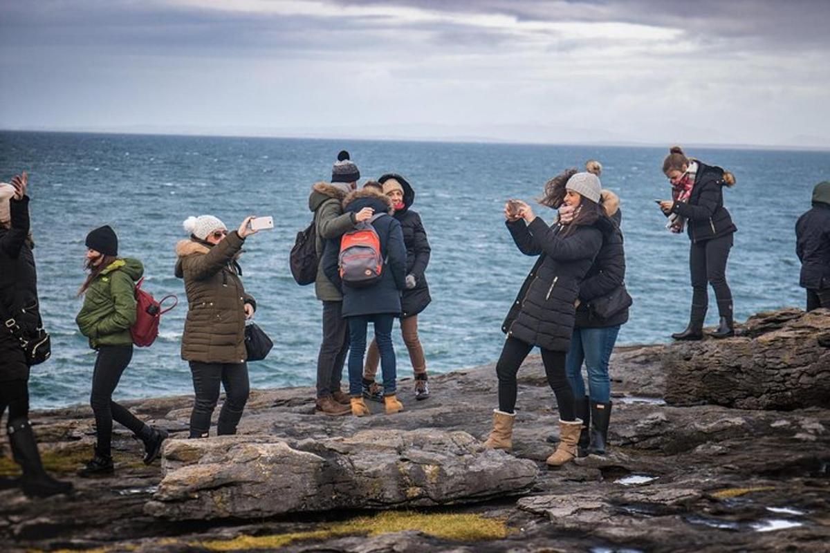 a group of people standing on rocks near the water