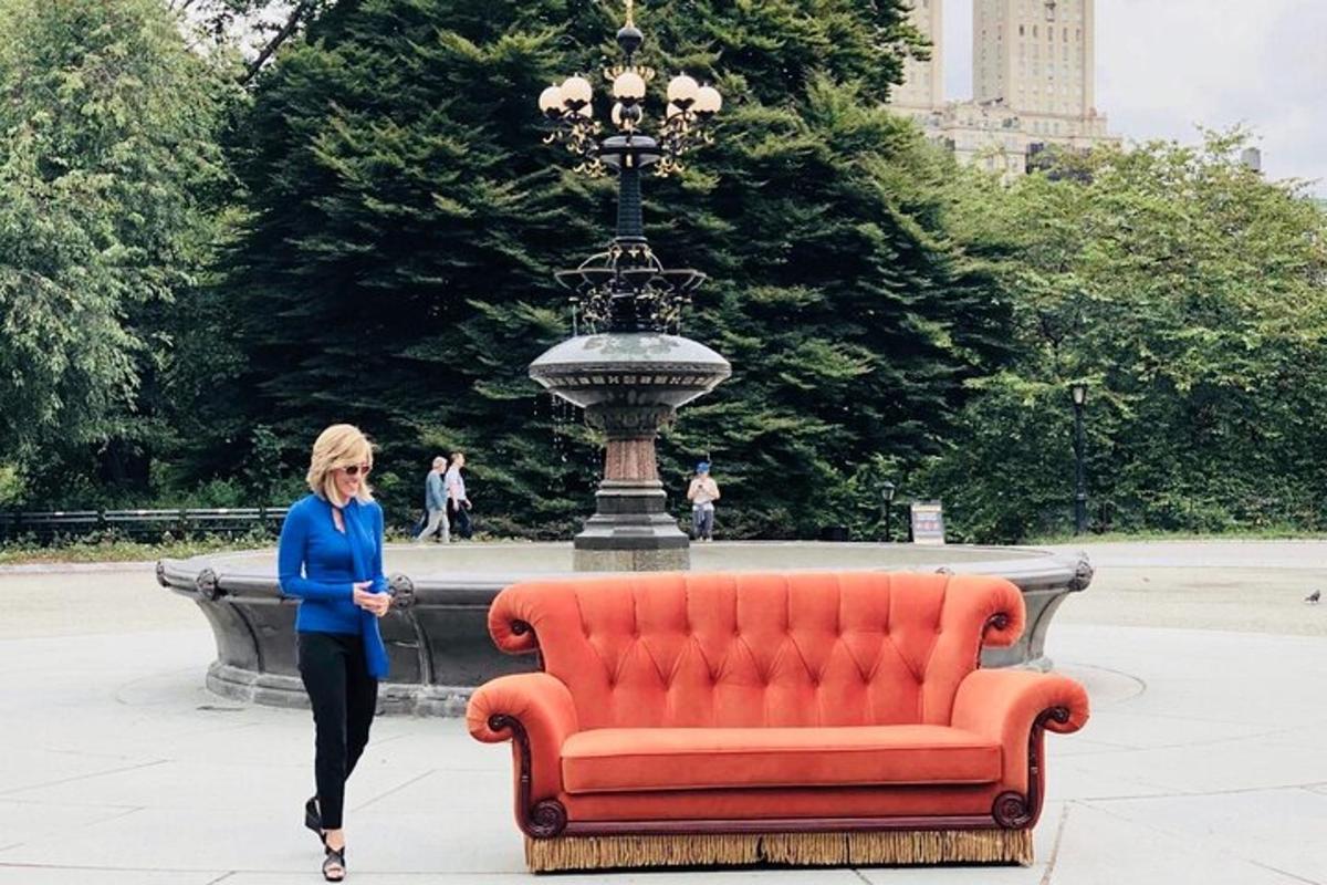 a woman walking past a orange couch in front of a fountain