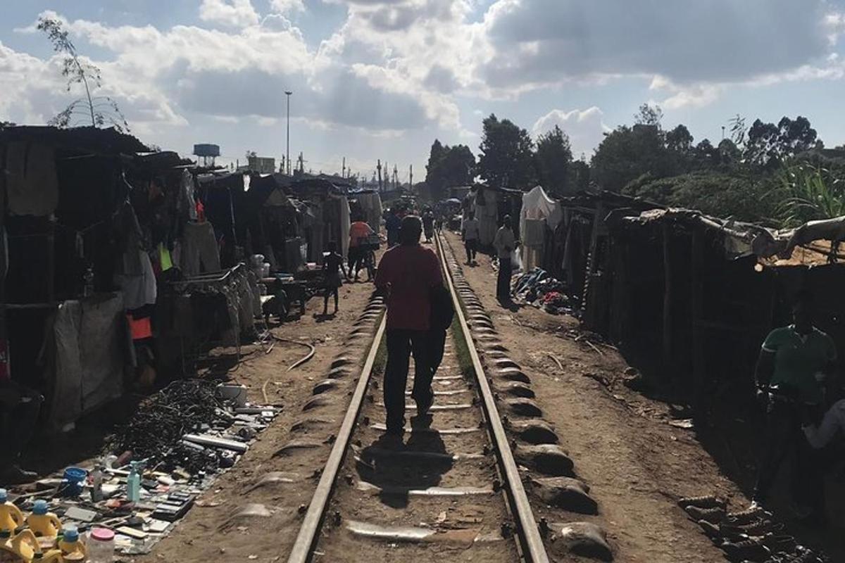 a man walking down a train track in a village