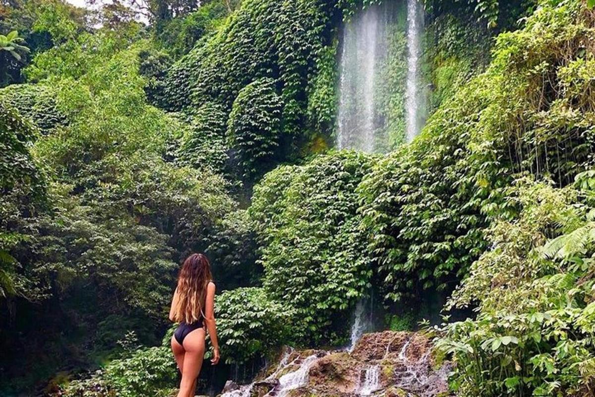 una donna in piedi su una roccia di fronte a una cascata