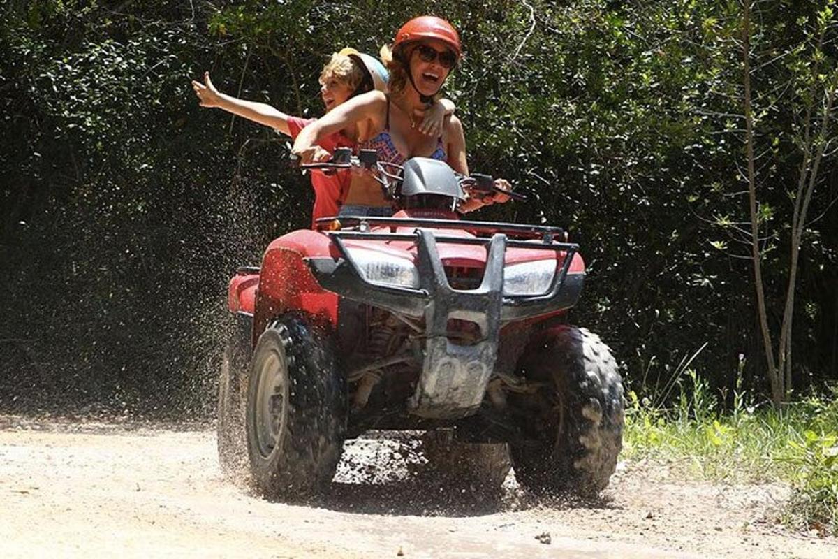 dva lidé jedoucí na čtyřkolce po nezpevněné cestě