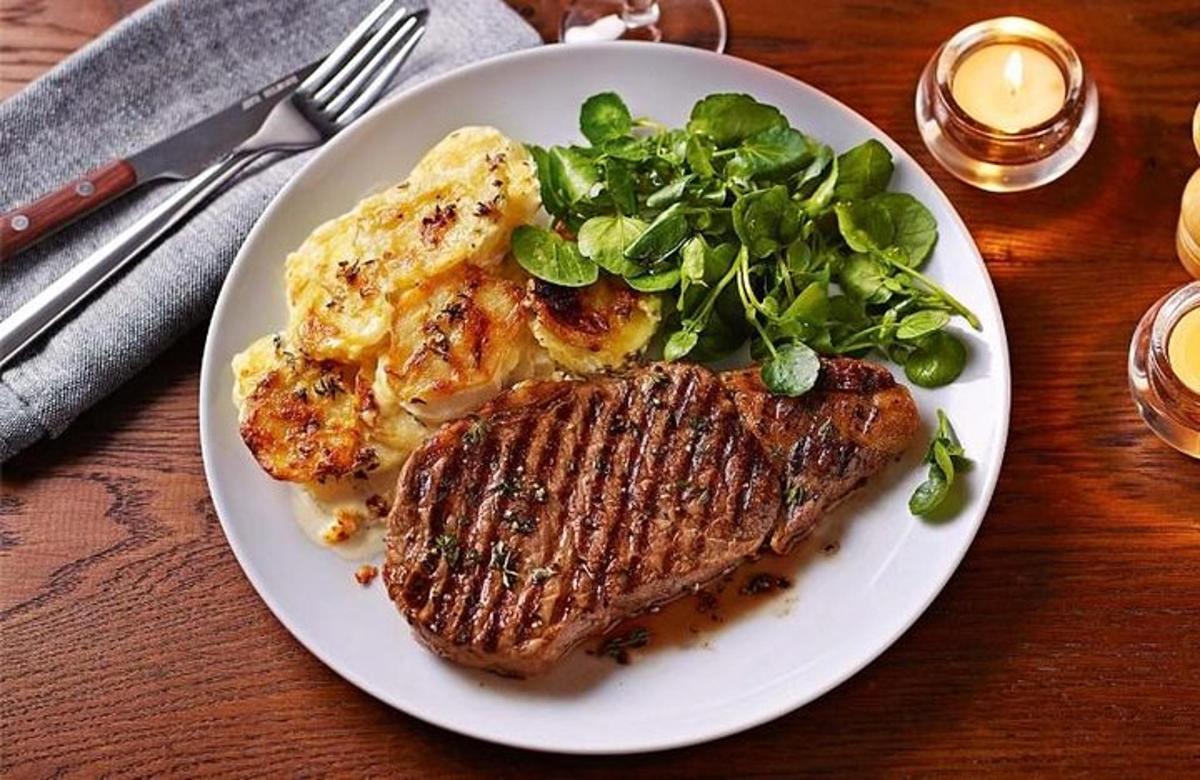 a plate of food with meat and greens on a table