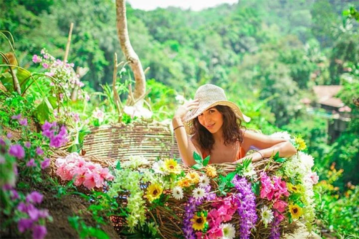 a woman in a hat sitting in a basket of flowers