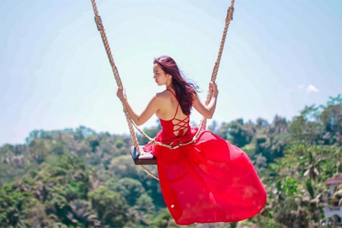 a woman in a red dress sitting on a swing