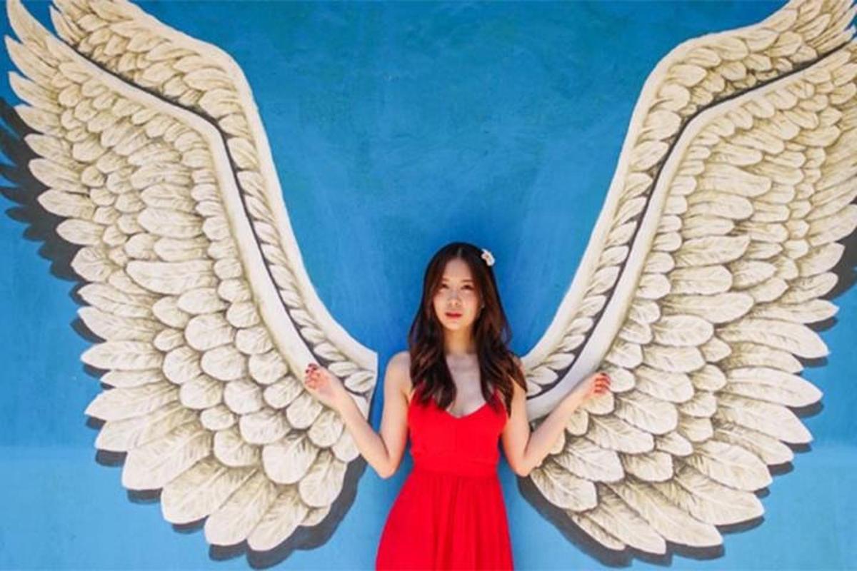 a girl in a red dress with white angel wings