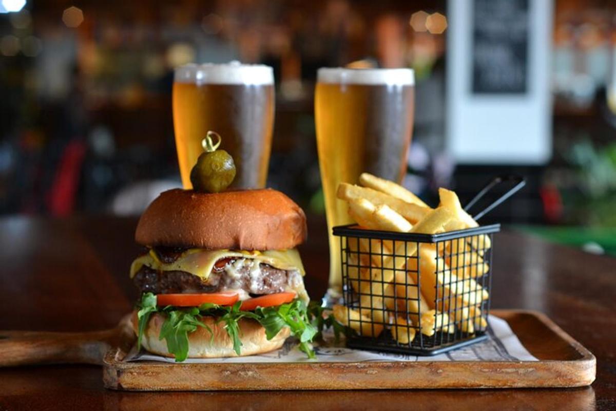 a hamburger and french fries and two glasses of beer