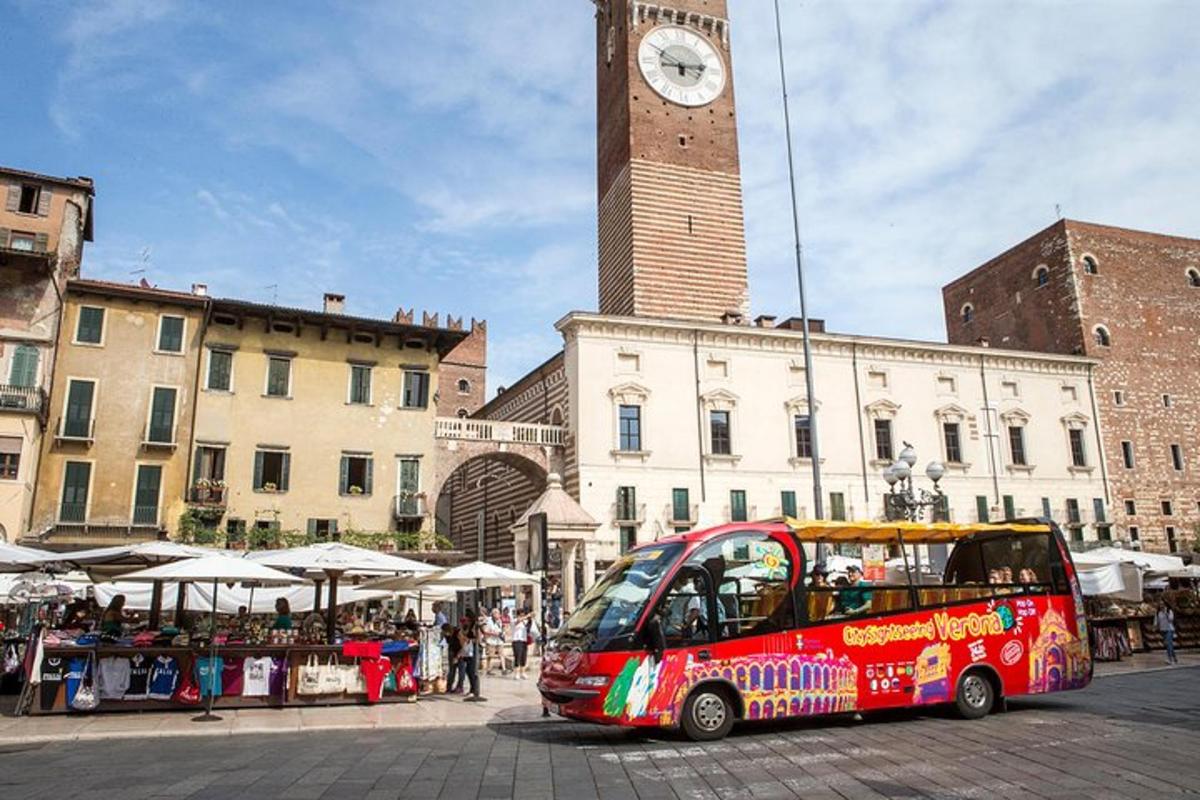 a red bus parked in front of a building with a clock tower