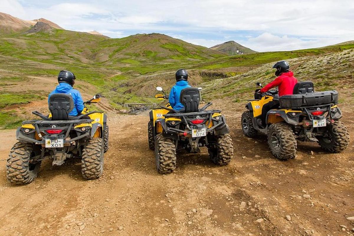 trei persoane pe ATV-uri pe un drum de pământ