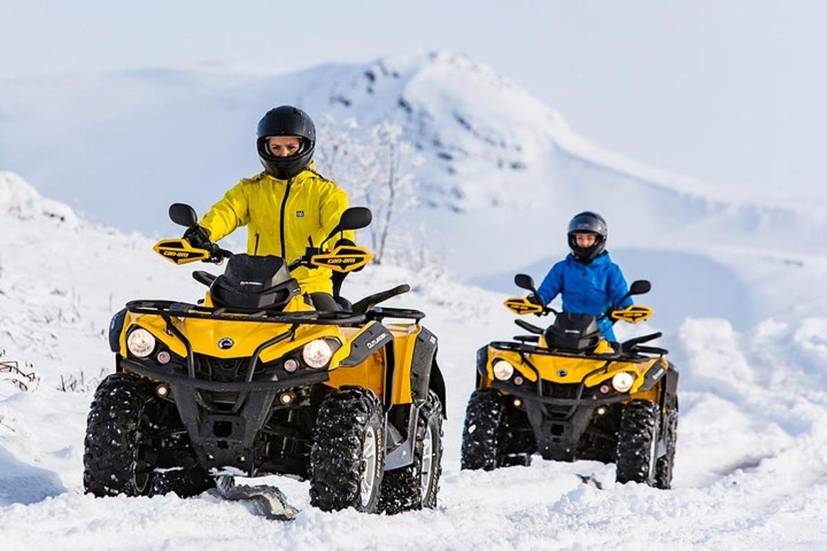 două persoane care călătoresc pe ATV-uri în zăpadă