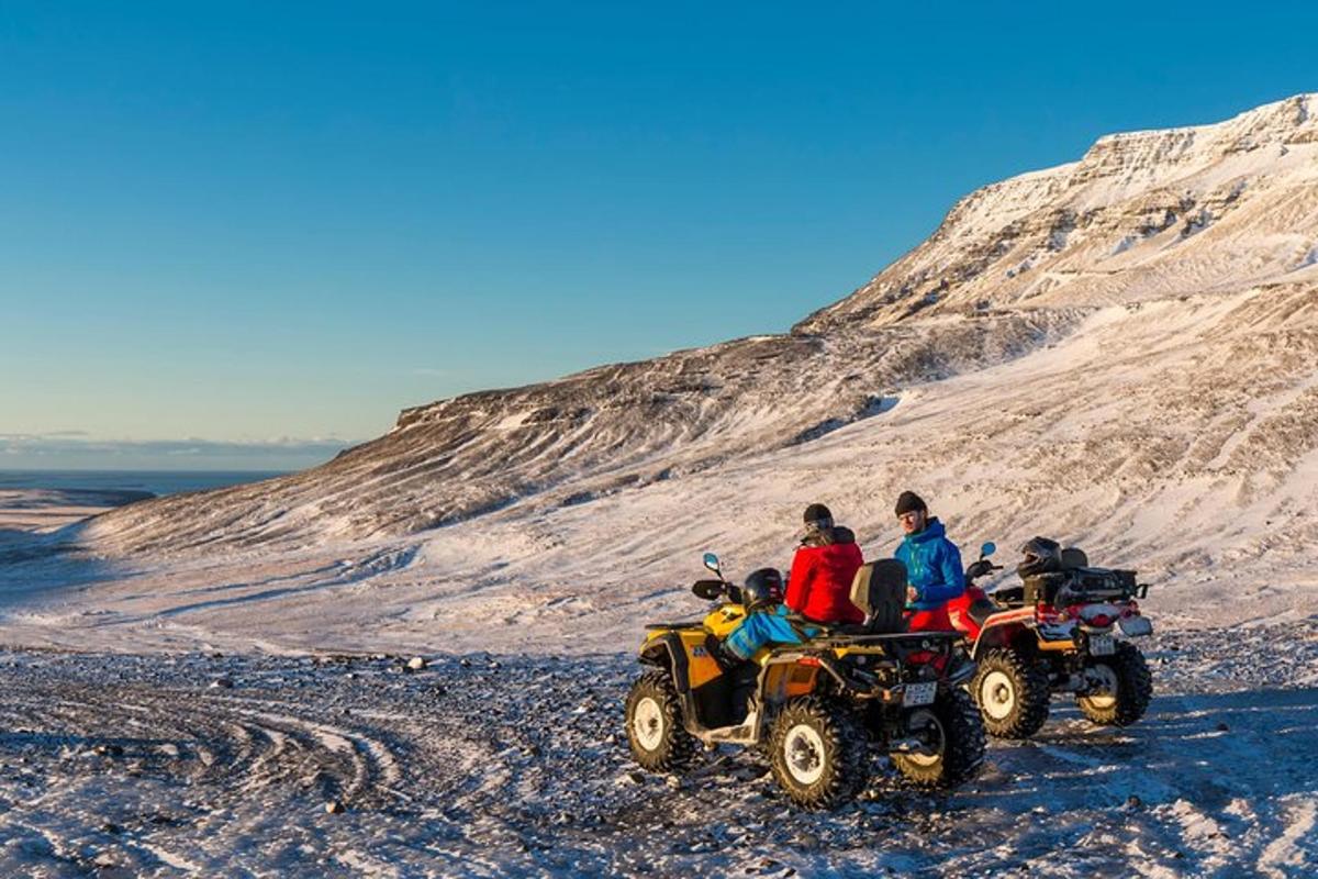 un grup de oameni care călătoresc cu ATV-uri pe un munte înzăpezit