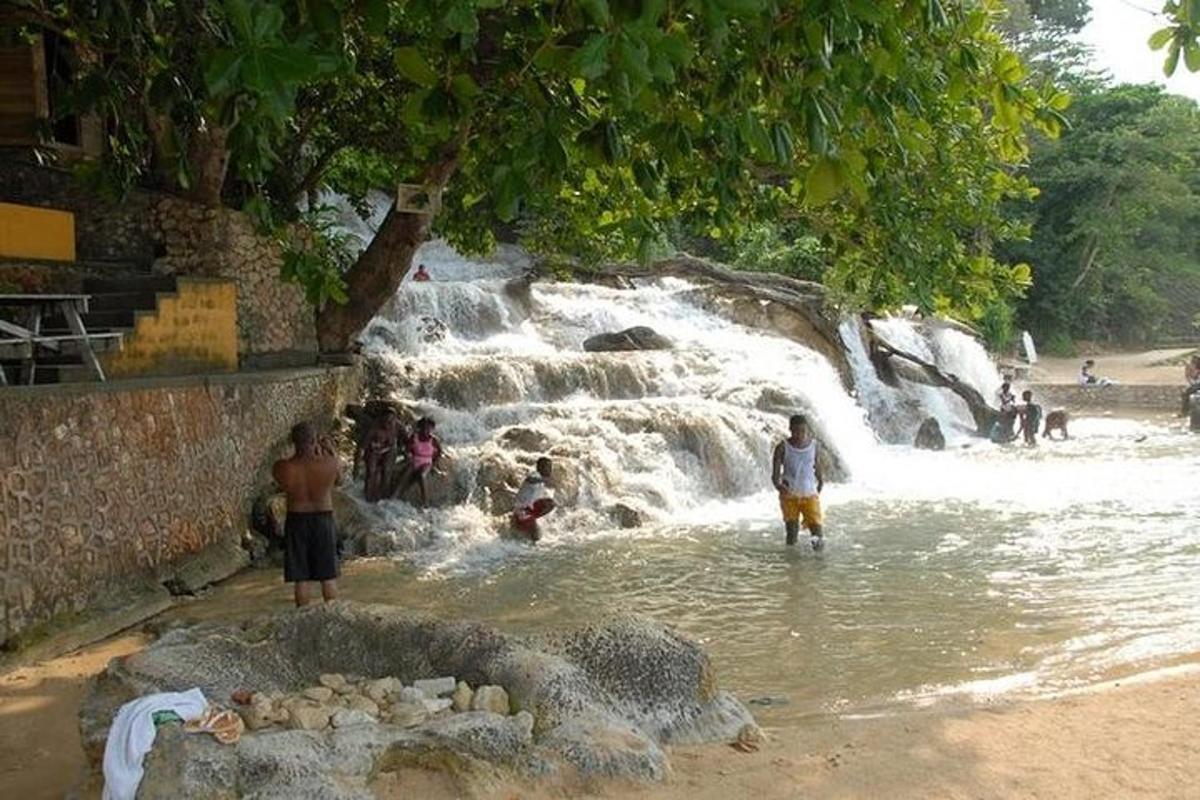 sekumpulan orang berdiri di dalam air berhampiran air terjun