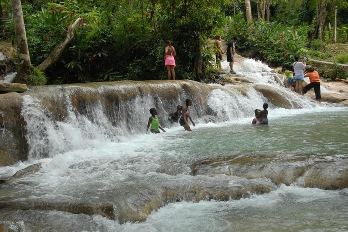 sekumpulan orang berdiri di dalam air di air terjun