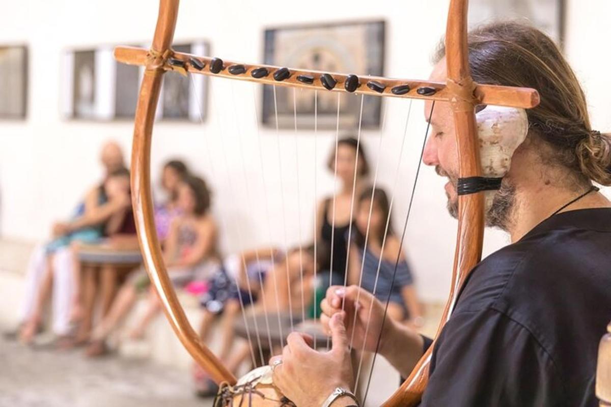 mężczyzna grający na instrumencie łuczniczym, w tle ludzie