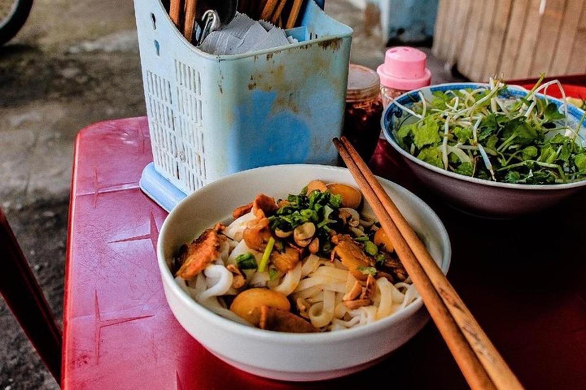 một bát thức ăn đặt trên bàn với đôi đũa