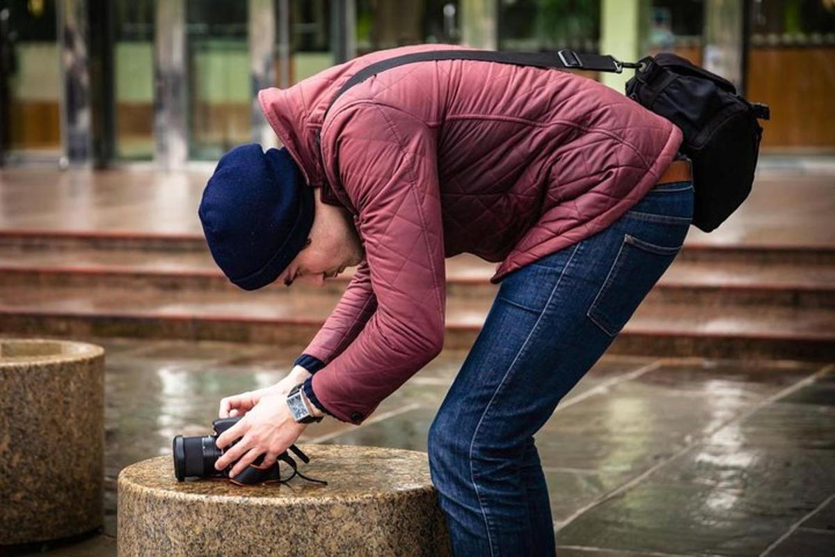 vyras, laikantis fotoaparatą ant stulpo