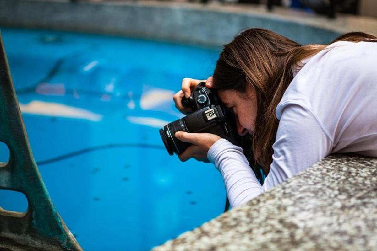 eine Frau, die mit einer Kamera ein Foto von einem Swimmingpool macht