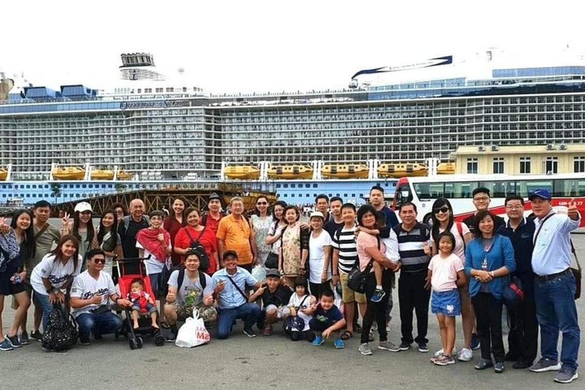 um grande grupo de pessoas em pé em frente a um navio de cruzeiro
